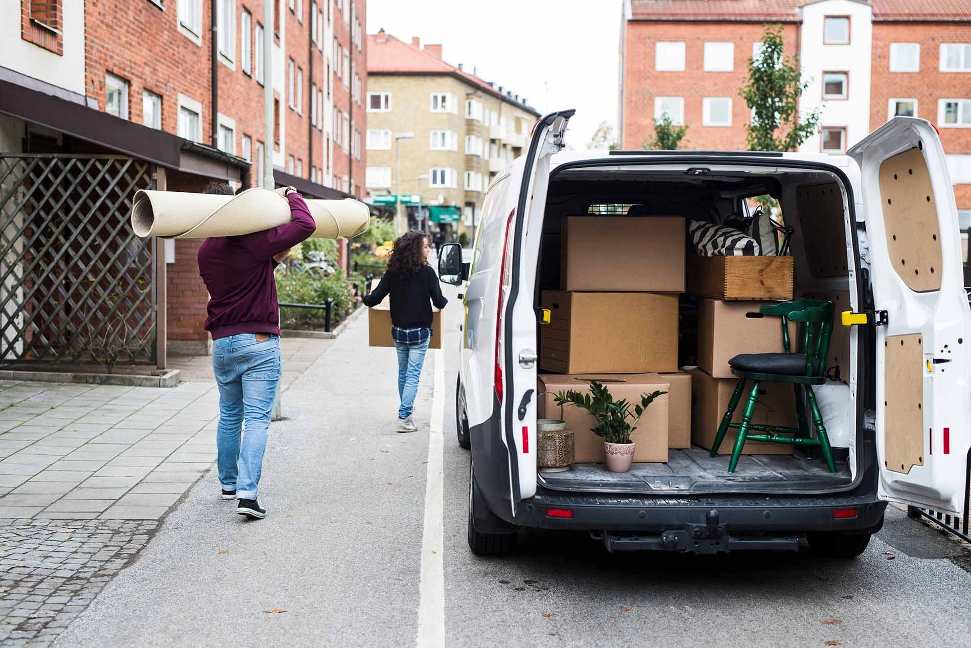 Umzug mit Transporter – Umzugshelfer laden Kartons in Lieferwagen